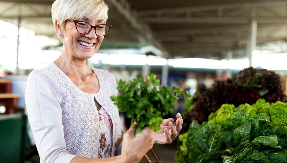 Smiling lady holds vegetables while market shopping near apache Junction, Arizona