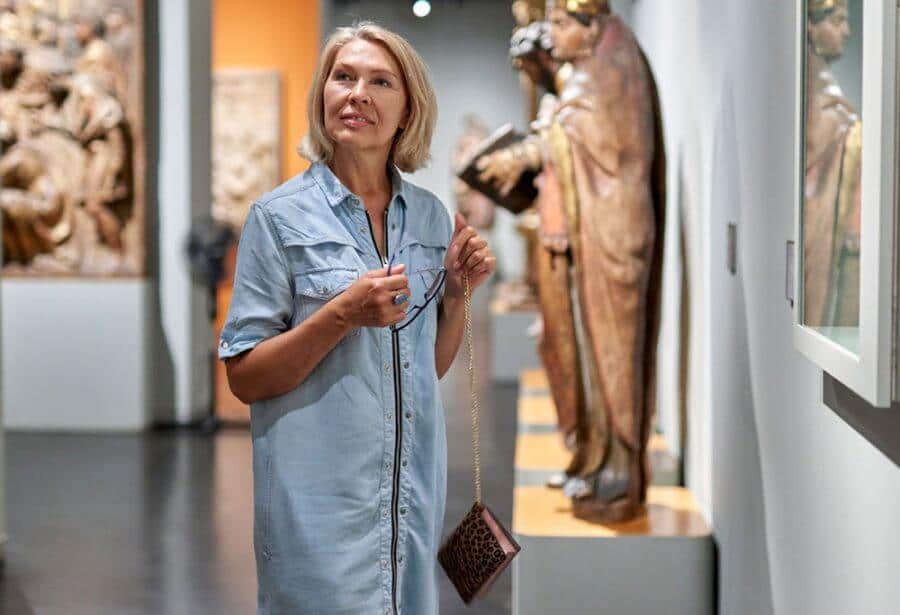 Lady observes art and sculptures nearbyy her while she visits a museum